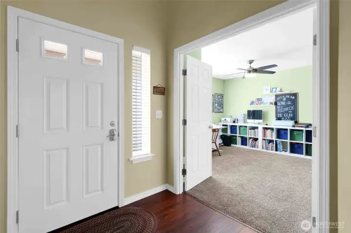 The bedroom/den with French doors has a ceiling fan and wall-to-wall carpeting.