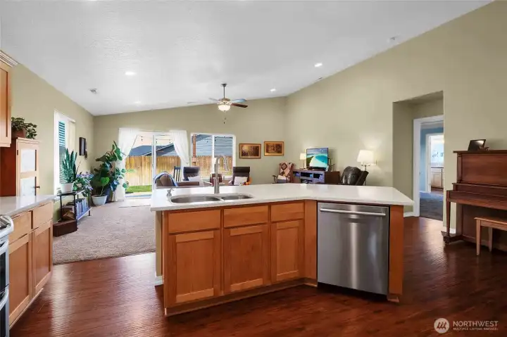 Airy open-concept living and kitchen space with vaulted ceilings, quartz island, rich wood tones, and seamless indoor-outdoor flow, create an inviting atmosphere for everyday living.