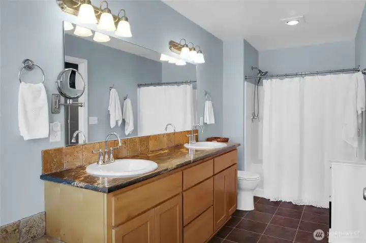 Primary bathroom with shower (and seat) and two sinks with very shiny faucets (showing meticulous care for their home).