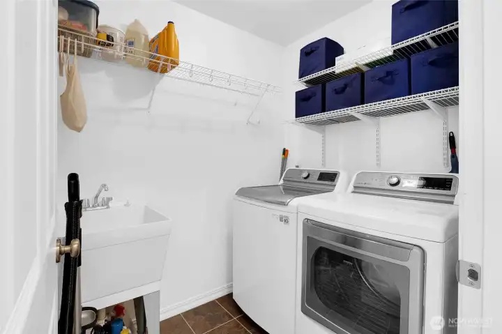 The laundry room features a washer, dryer, and utility sink and several shelves for keeping your supplies organized.