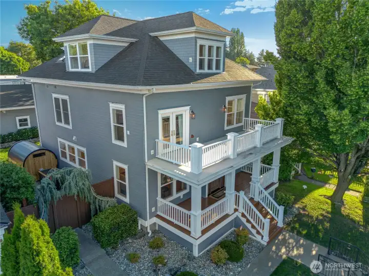 The aerial view tells the full story — three floors, upper balcony, cedar barrel sauna, and StruXure pergola with integrated heaters. The scale of this rebuild is immediately apparent. A 36x30 heated garage with solar panels sits beyond the fully fenced yard.