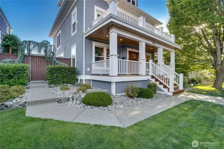 The wraparound porch with cedar tongue-and-groove ceiling, recessed lighting, and freshly re-stained decking sets the tone before you step inside. Mature landscaping, river rock hardscaping, and the three-story profile communicate both character and scale.
