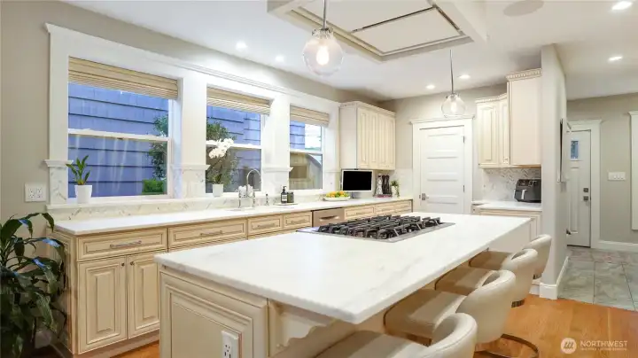 A 15’9” x 19’5” kitchen built for how people actually live. Calacatta marble island with 6-burner gas cooktop, Rohl faucets at the sink, herringbone marble backsplash, custom glazed cabinetry with crown detail, and a tray ceiling with globe pendants. Butler’s pantry and mud room all connect off this space.
