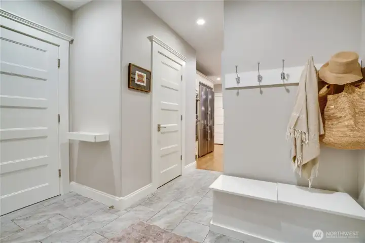A proper mud room off the back door — built-in bench, hook rail, tile floor transition from the hardwood, and a direct sight line through to the Liebherr refrigerator. For a family with older kids, this is the detail that makes the home function. Everything has a place before it enters the main living spaces.