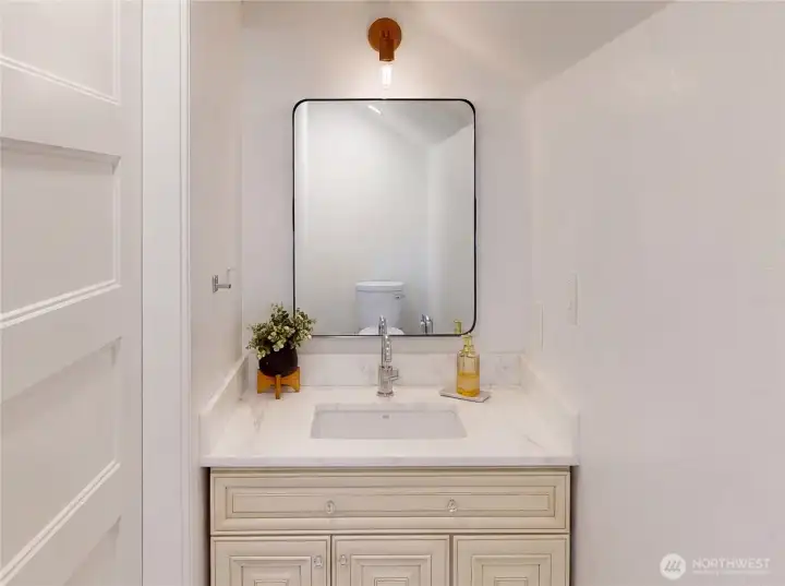The main floor powder room — Carrara marble counter, Rohl faucet, matching custom glazed vanity, brass sconce, and black-framed mirror. Perfectly proportioned and finished with the same consistency as every other bath in the home. The detail here signals that nothing was an afterthought.