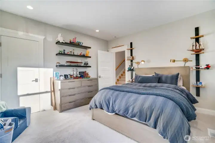 One of three bedrooms on the second floor — tree canopy views, clean neutral finishes, recessed lighting, and automated blackout blinds. The second floor also includes the primary suite, a full bath, laundry, and an additional bedroom not pictured