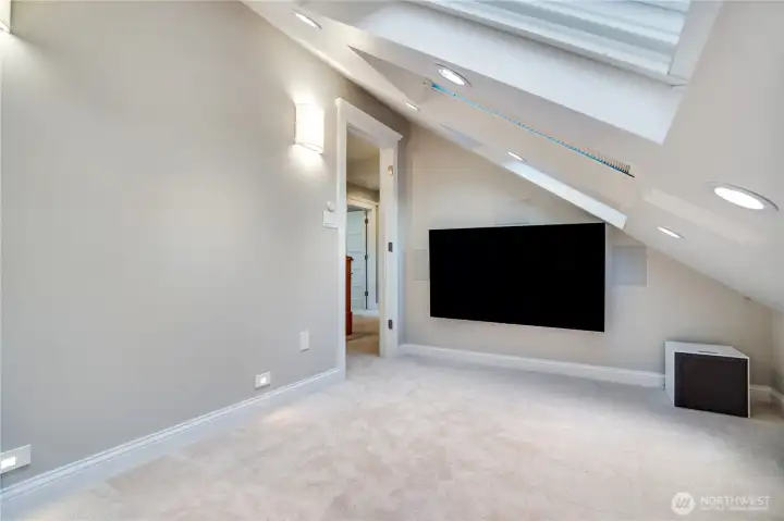 Large-format display, in-ceiling surround sound, and a sight line to the hallway beyond. Everything this floor needs — nothing it doesn't.