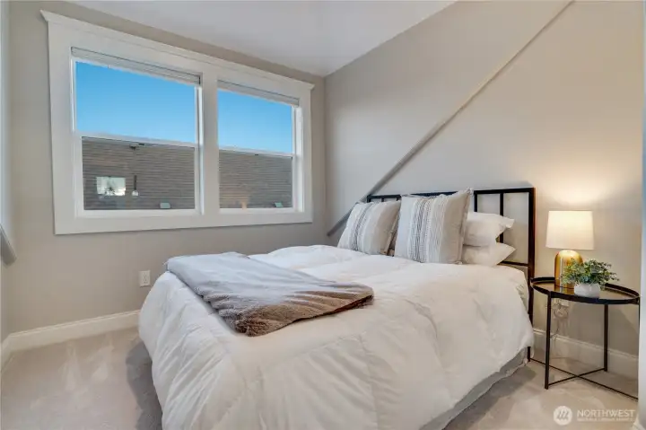 A third floor bedroom with roofline character, double windows with tree canopy views, neutral carpet, and clean finishes throughout. Blackout remote-controlled blinds. Works equally well as a bedroom, creative studio, or private guest suite with access to the dedicated third floor bath.