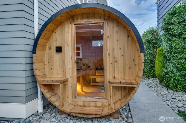 A cedar barrel sauna with glass door entry, interior bench seating, and a Harvia heater — lit from within and ready. This is not a spa amenity added as an afterthought. It is a daily wellness feature positioned steps from the cold plunge and the back door of the home.