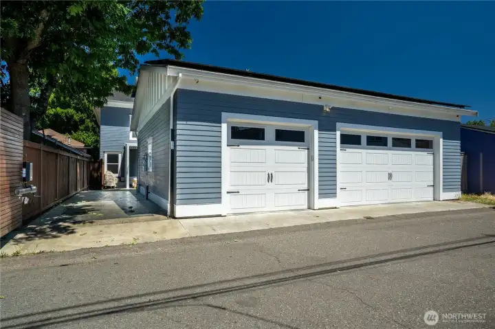 Two carriage-style garage doors with transom windows, matching siding, and a sealed concrete apron — accessed directly from the alley. Solar panels on the south-facing roof offset approximately 50% of energy costs. Inside: 36x30 with tall ceilings, gas heater maintained at 70 degrees year-round, fiber optic connection to the home's commercial-grade internet system, and storage at a scale that changes how a household operates. This is not a standard detached garage.