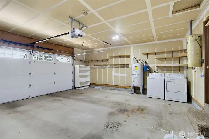 Oversized two car garage with shelving and washer and dryer.
