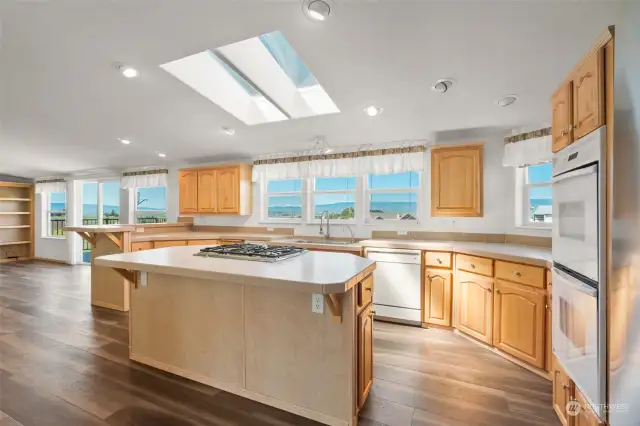 Bright and open kitchen with gas cooktop and double ovens.