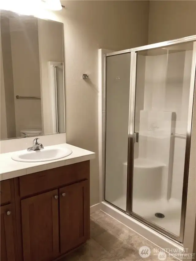 The main bathroom features tile counters and large shower.