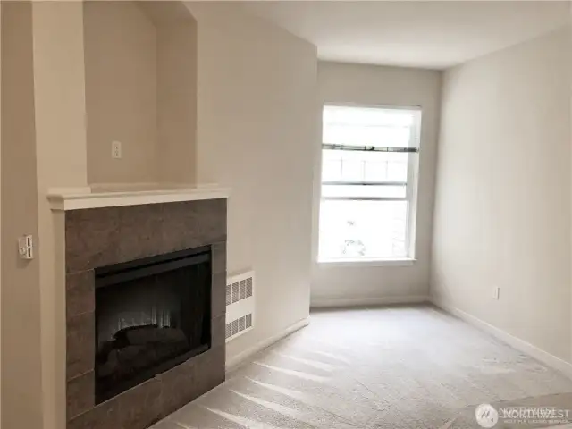 Primary bedroom featuring gas fireplace and view toward greenbelt area.