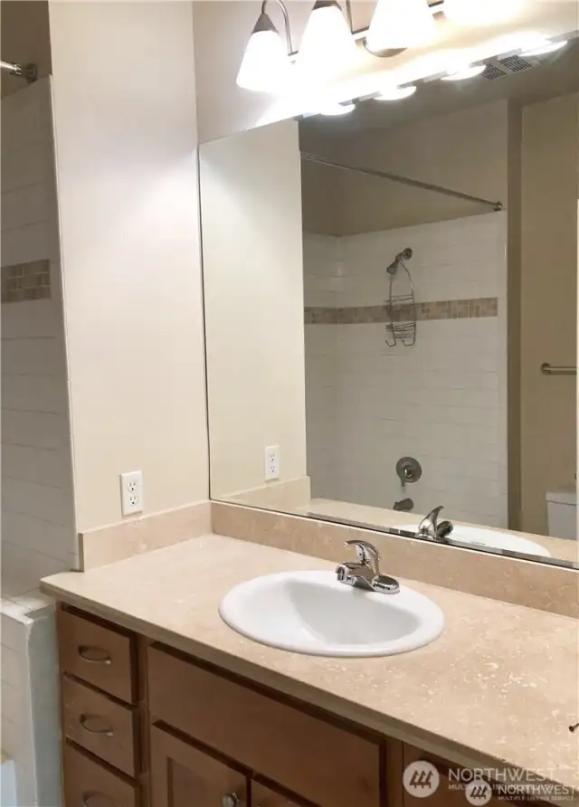 Primary bathroom features quartz counters and tile tub/shower surround.