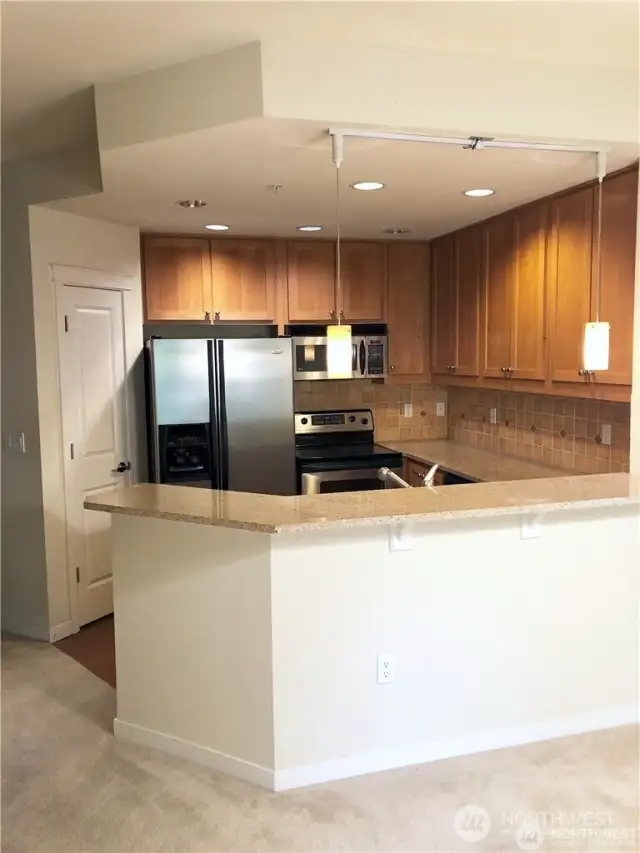 Quartz counters with tile backsplash. Kitchen is light and bright and features built-in microwave.