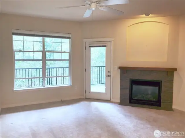 Living room features ceiling fan, gas fireplace, plenty of light, and a door to the generous balcony.
