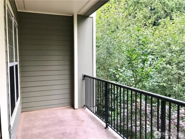 Another view of the balcony. The view looks out over a forested area that is peaceful and serene.