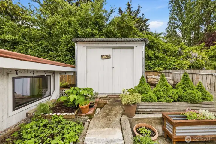 Additional storage shed provides convenient space for gardening tools and outdoor equipment.