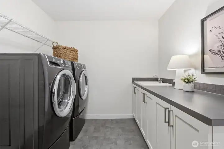 The oversized upstairs laundry room features dual access, folding counters, and a utility sink for everyday convenience.