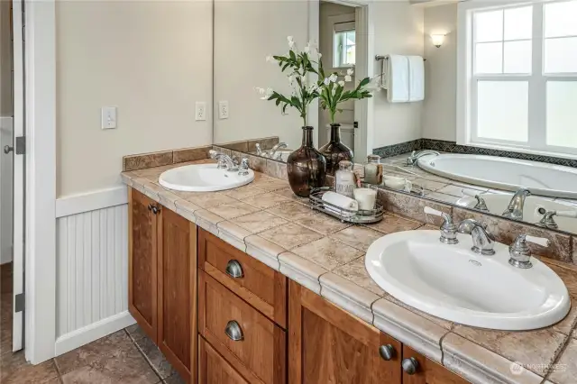 The 5-piece primary bathroom with tiled floors and shower, large soaking tub and dual sinks.