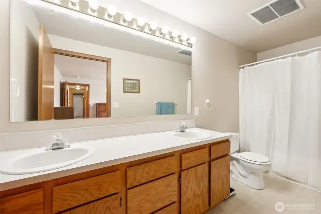 In the primary suite, double sinks for superior elbow room, oak cabinets keep your beauty stash organized, and vinyl floors are as practical as they are durable. Plus, the lighting above this huge mirror? Instagram-ready every day.