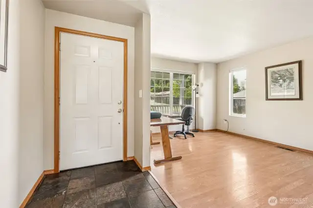 Meet the entryway that moonlights as a mood board with dark slate, crisp white door, warm laminate floors, and just enough windows to make your houseplants swoon.