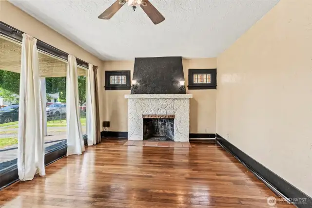 Living room with statement fireplace and HUGE front window that shines loads of natural light on hardwood floors
