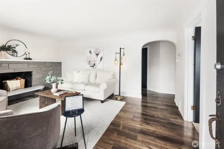 Warm wood floors and a classic stone fireplace create a timeless living room that’s both stylish and welcoming.