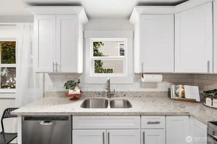 Bright white cabinetry, sleek stainless appliances, and warm wood floors make this kitchen the perfect blend of modern design and everyday comfort.