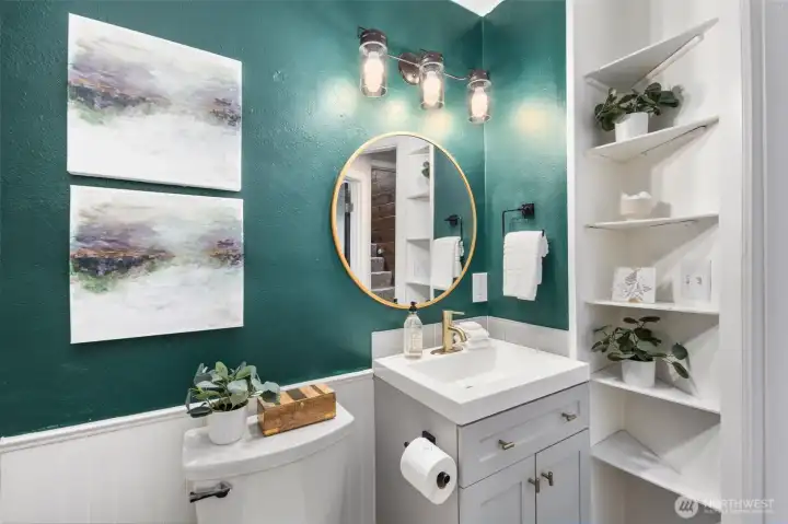 Gold fixtures, open shelving, and a statement mirror make this bathroom both practical and polished.