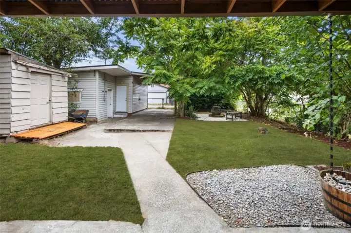 Private backyard retreat with mature trees and a cozy fire pit area, perfect for evenings under the stars.