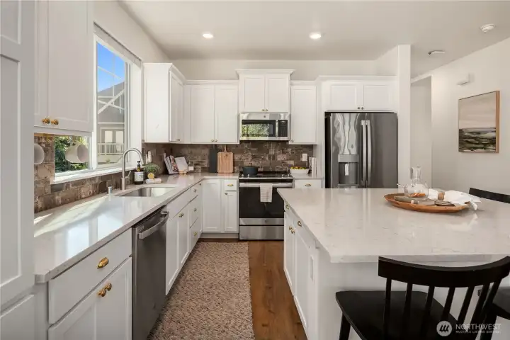 Sleek quartz counters flow into a distressed tile backsplash.