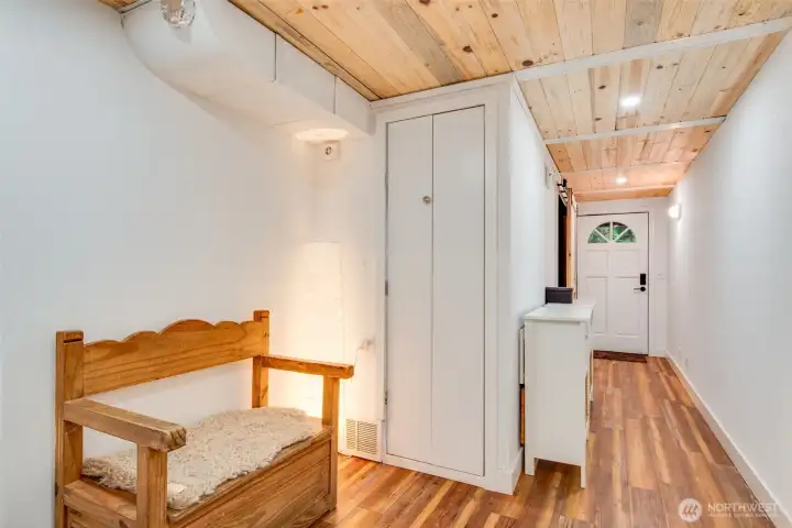 Downstairs hallway with multiple closet spaces and door to backyard patio as well as second entryway to the garage, workshop and home office space.