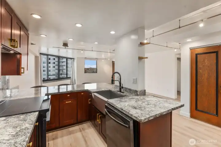 Modern open-concept kitchen farmhouse apron sink, custom wood cabinetry, and bar seating overlooking the light-filled living space.