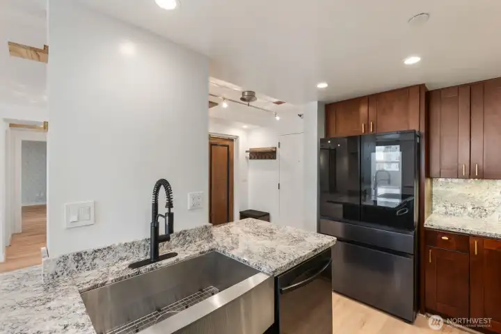 Thoughtfully designed kitchen with updated appliances, deep apron sink, modern black fixtures, and a layout that connects naturally to the entry and main living space.