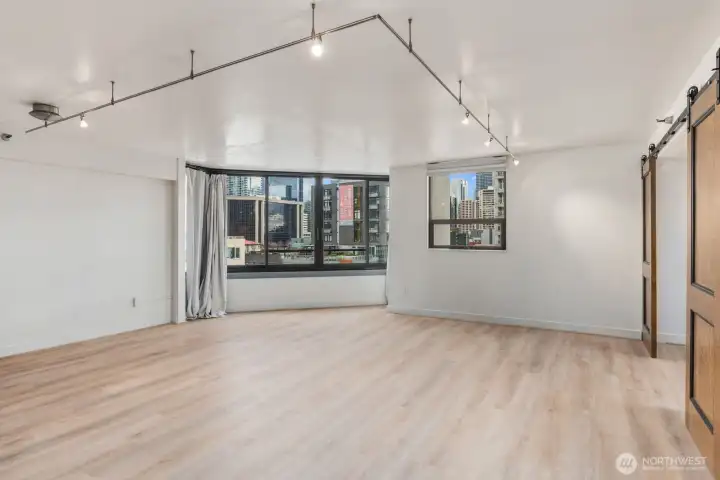 Spacious urban condo living area with large windows with surrounding city views, and an open layout designed for flexible living and entertaining.