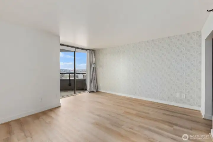 Bright Seattle condo living space with an accent wall, and sliding glass doors leading to a private balcony with water views.