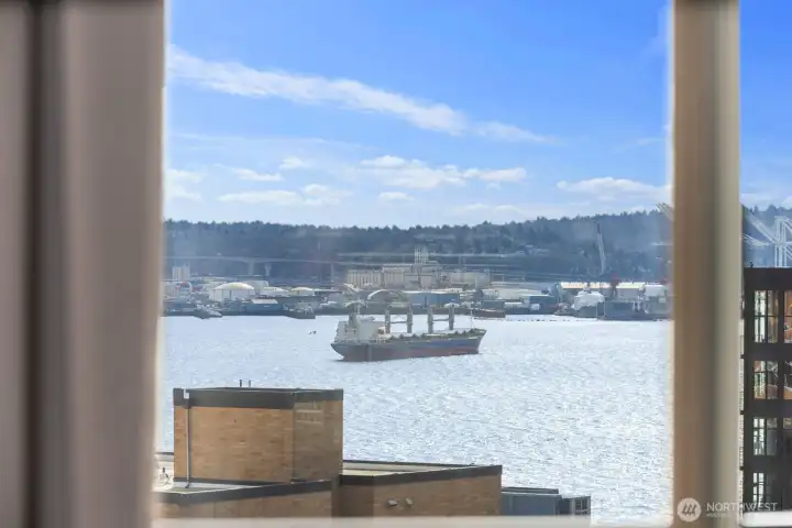 Puget Sound water view with working waterfront activity, cargo vessel traffic, and surrounding shoreline visible across the harbor.