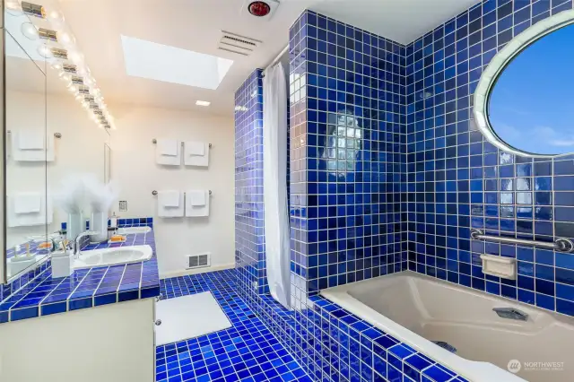 Large tiled primary bath with separate shower & soaking tub. The skylight and porthole window bring in excellent natural light