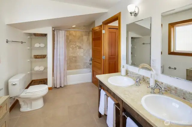 Primary full bath with double sinks and storage. A large walk-in closet with shelving adjoins.