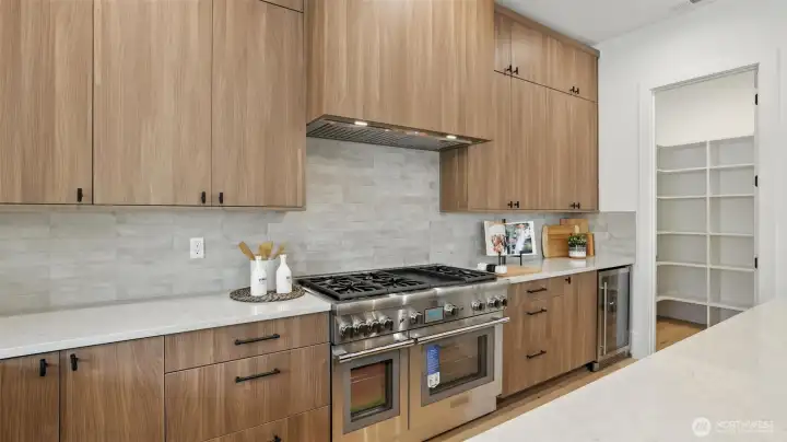 The kitchen pairs clean architectural lines with functional luxury — professional-grade appliances, a Thermador double-oven gas range, soft-close cabinetry, and a generous walk-in pantry ready for effortless hosting. The oversized island centers the home, perfect for morning coffee, casual meals, or lively evenings with friends. Every detail reflects craftsmanship that balances sophistication with ease.