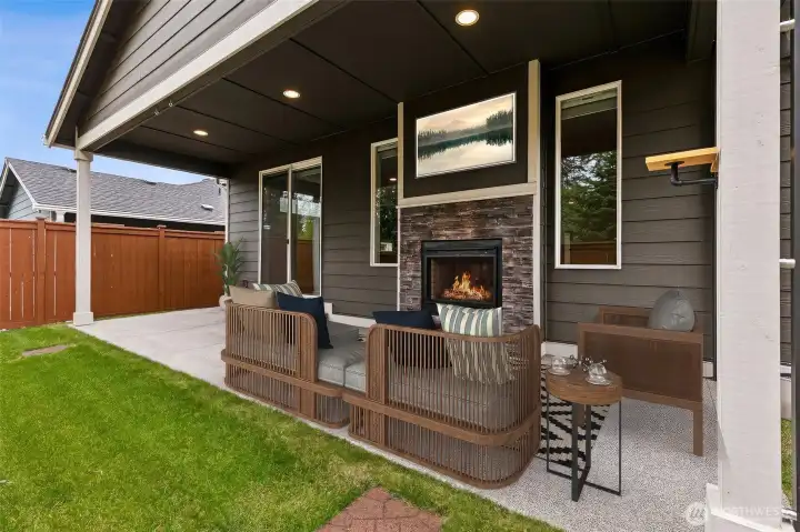 If the Pacific Northwest had a perfect outdoor room, it might look a lot like this. The covered patio combines comfort, warmth and practicality with recessed lighting, generous seating space and a beautiful double-sided gas fireplace wrapped in handsome stacked stone. Because the fireplace is shared with the living room inside, it creates a wonderful visual connection between the indoor and outdoor spaces while extending the usefulness of the patio well beyond summer. Electrical has already been installed above the fireplace for a future television, and the nearby sliding glass door keeps everything connected to the dining room and kitchen for easy entertaining. The electric smoker remain with the home as well, making it easy to start planning your first gathering before you've even unpacked. Whether it's coffee on a rainy morning or friends around the fire on a cool evening, this space is ready for all four seasons.