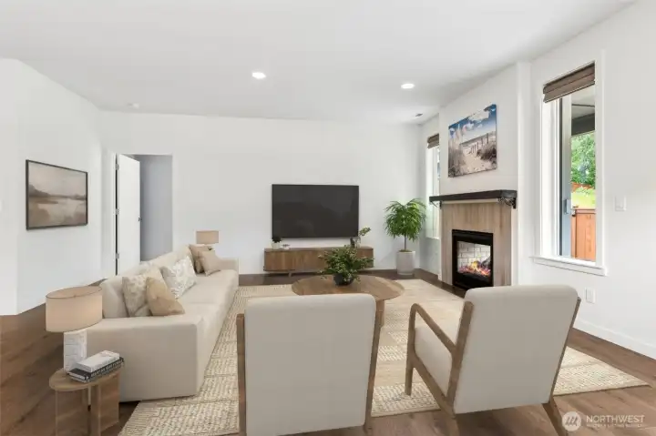 The living room connects effortlessly to the kitchen and dining area, creating an easy flow that works equally well for entertaining a crowd or enjoying a peaceful evening at home. Anchoring the room is a stylish gas fireplace featuring a substantial dark mantel and a sleek contemporary surround that gives the space a polished, updated feel. The look is sophisticated without being fussy and provides a beautiful backdrop for furniture placement and seasonal decorating. From here you can also catch a glimpse of the primary suite entry, reinforcing how well this floorplan balances connected living spaces with private retreats.