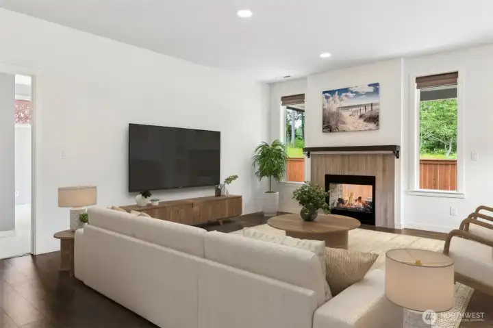 This fireplace is one of the coolest features in the home. The sleek double-sided design allows it to serve both the living room and the covered outdoor patio, creating year-round enjoyment whether you're relaxing inside or entertaining outdoors. From this angle, you can actually see through the glass on both sides of the fireplace toward the patio beyond, a subtle detail that adds visual interest and helps connect the indoor and outdoor living spaces. Framing the fireplace are two tall portrait-style windows that draw your eye directly toward the protected wetlands behind the home, bringing natural beauty into the room without sacrificing privacy. The combination of the contemporary fireplace, nature views and open-concept layout creates a living space that feels both cozy and connected.