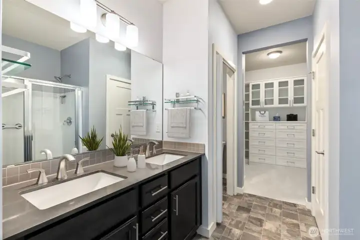 The oversized dual vanity is topped with elegant quartz counters and finished in a gorgeous mushroom-brown tone that adds warmth and depth to the space, while abundant drawers and cabinet storage help keep countertops clear and clutter at bay. A private toilet room offers an extra layer of convenience, and the generously sized linen closet located nearby means there is a dedicated place for everything from towels to extra supplies. Just beyond, the large walk-in closet completes the suite, creating a thoughtfully designed arrangement that makes everyday routines feel effortless.