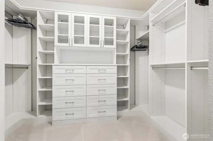 If you've ever dreamed of having a closet that actually keeps up with your wardrobe instead of constantly negotiating with it, you'll appreciate this space. The custom California Closets system transforms this oversized walk-in into a beautifully organized retreat complete with glass-front display cabinets for favorite accessories, convenient drawer storage below and generous shelving above for even more storage flexibility. Every inch has been thoughtfully utilized without feeling crowded, and the brand-new carpeting adds warmth and comfort underfoot.