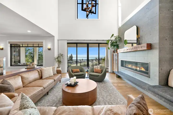 The living room creates a warm and inviting atmosphere with the gorgeous fireplace, vaulted ceilings and water views.