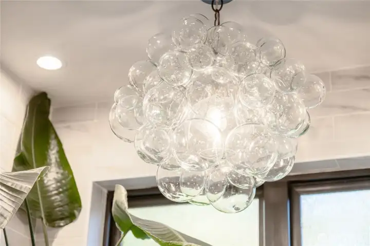 Stunning designer light fixtures like this one in the primary suite leave a lasting impression in virtually every room.