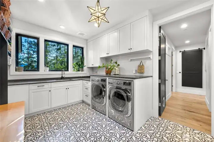 Oversized mud room with custom cabinetry, heated tile floors, granite countertops, and oversized LG washer and dryer.